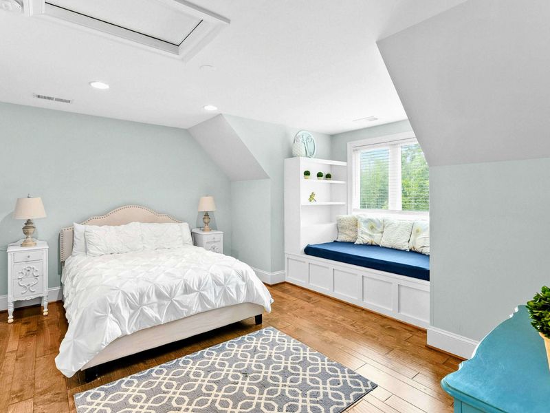 A charming bedroom with a king bed, a built-in window seat, stylish decor, and an ensuite bathroom for added comfort.