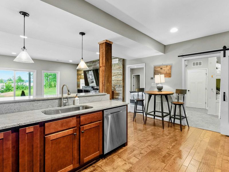 A cozy lower-level kitchen with modern appliances, a rustic accent bar, seating areas, and direct access to the living space and backyard.