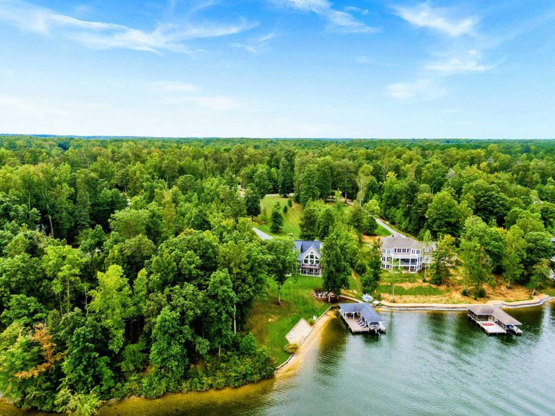 A picturesque lakeside property featuring a spacious home, private dock, sandy shoreline, and lush greenery for a tranquil retreat.