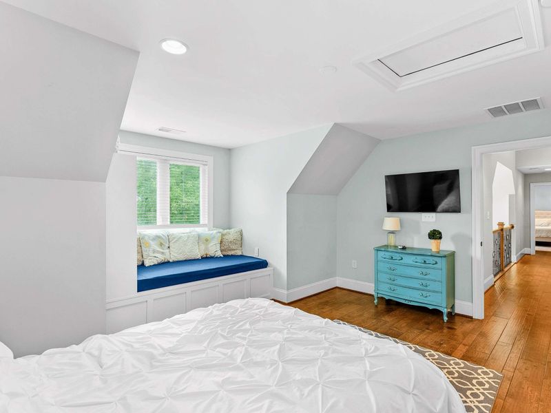 A charming bedroom with a king bed, a built-in window seat, stylish decor, and an ensuite bathroom for added comfort.