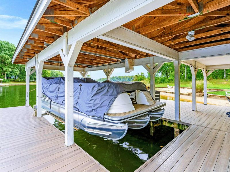 A picturesque waterfront dock featuring covered seating, lounge chairs, and easy access to the sandy beach and spacious backyard.