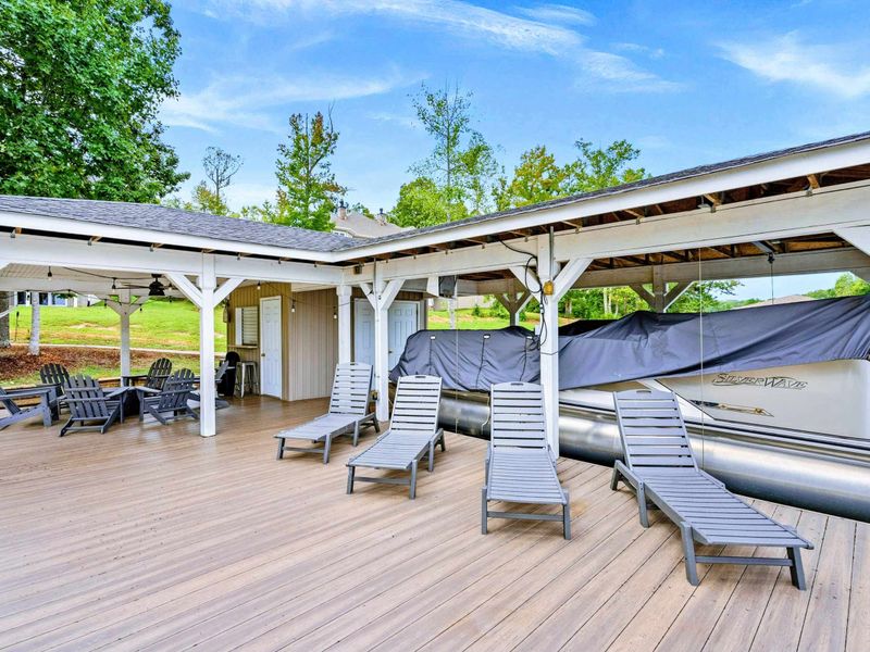 A picturesque waterfront dock featuring covered seating, lounge chairs, and easy access to the sandy beach and spacious backyard.
