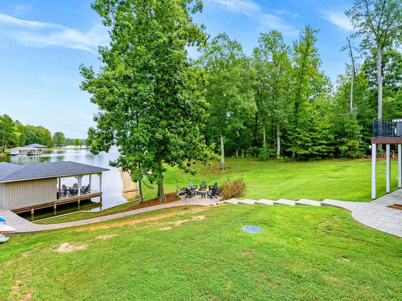 A picturesque waterfront dock featuring covered seating, lounge chairs, and easy access to the sandy beach and spacious backyard.