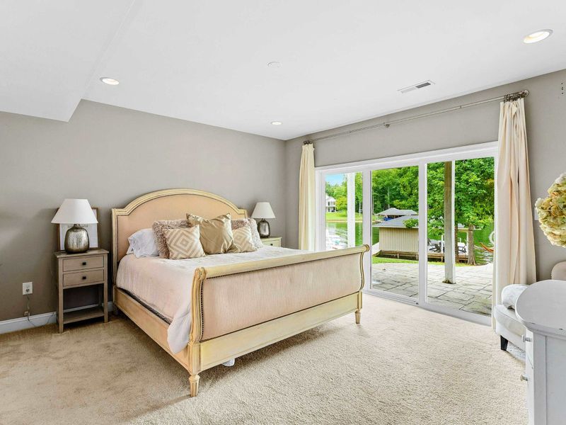 A tranquil bedroom with a king bed, cozy decor, sliding glass doors opening to a patio with lush outdoor views, and an ensuite bathroom for added convenience.