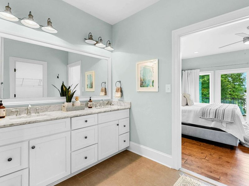 A luxurious ensuite bathroom featuring a double vanity with ample storage, a glass-enclosed rainfall shower, a soaking tub, and elegant marble finishes.