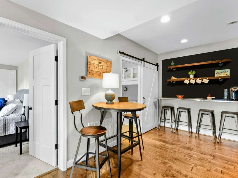 A stylish coffee nook with barstool seating, a cozy table, and modern decor conveniently located near bedrooms and other living spaces.