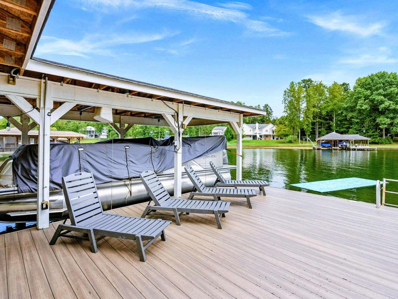 A picturesque waterfront dock featuring covered seating, lounge chairs, and easy access to the sandy beach and spacious backyard.