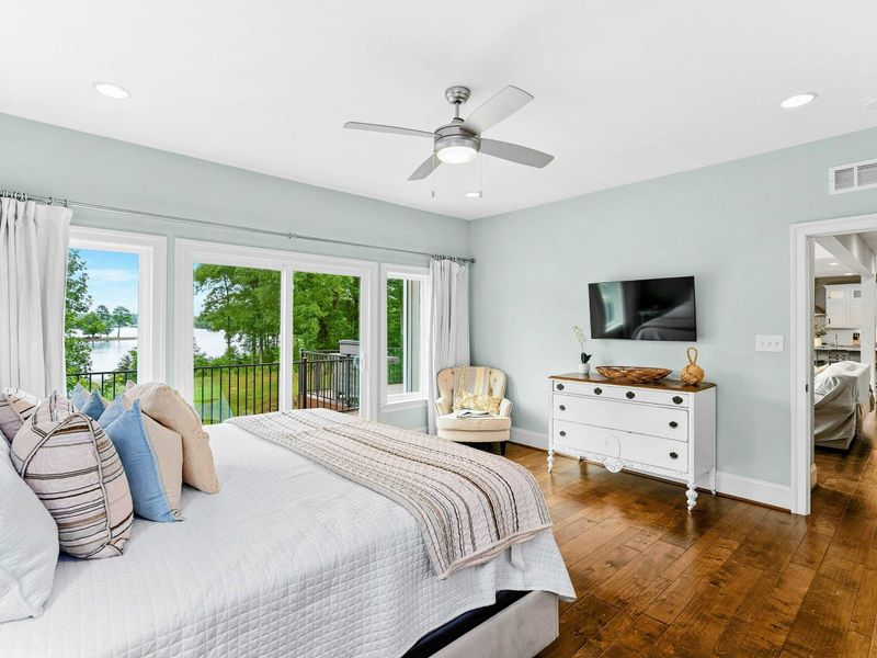 A bright and inviting Primary Bedroom featuring a king bed, cozy decor, sliding doors opening to a private balcony with serene views, and an ensuite bathroom.
