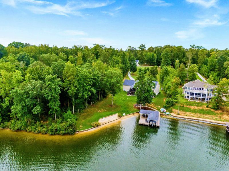 A picturesque lakeside property featuring a spacious home, private dock, sandy shoreline, and lush greenery for a tranquil retreat.