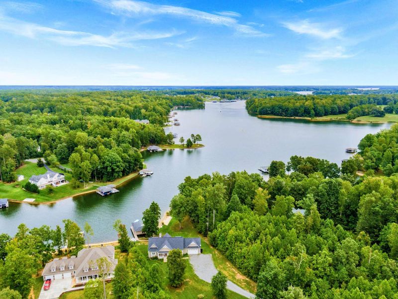 A picturesque lakeside property featuring a spacious home, private dock, sandy shoreline, and lush greenery for a tranquil retreat.
