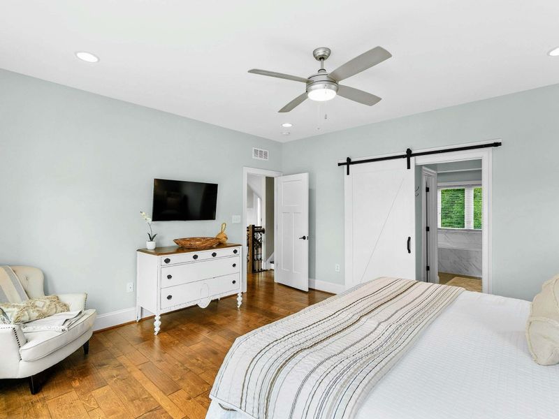 A bright and inviting Primary Bedroom featuring a king bed, cozy decor, sliding doors opening to a private balcony with serene views, and an ensuite bathroom.