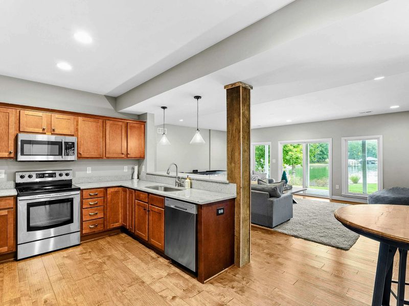 A cozy lower-level kitchen with modern appliances, a rustic accent bar, seating areas, and direct access to the living space and backyard.