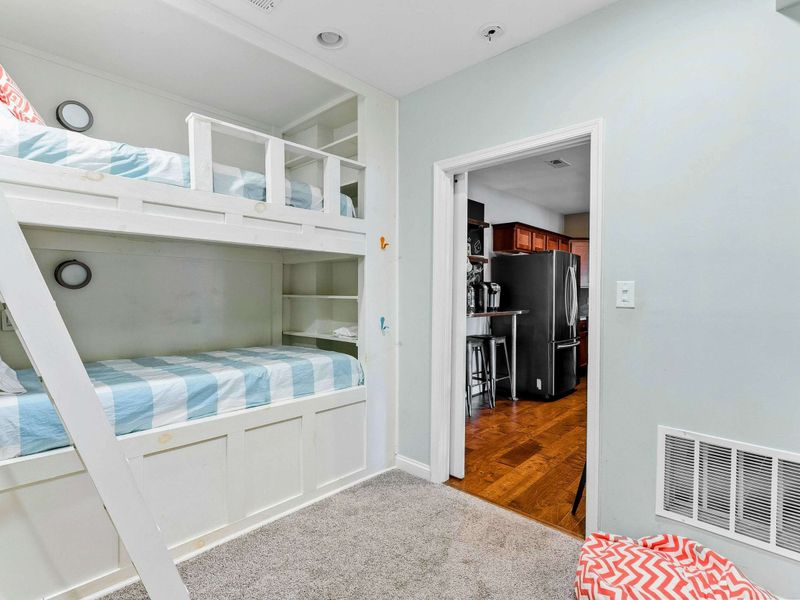A fun and cozy bunk room featuring built-in beds, a large TV, ample storage for toys and games, and easy access to the main living areas.