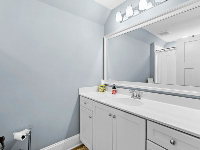 A clean and spacious bathroom featuring a large vanity with ample counter space, a soft blue color palette, and modern lighting.
