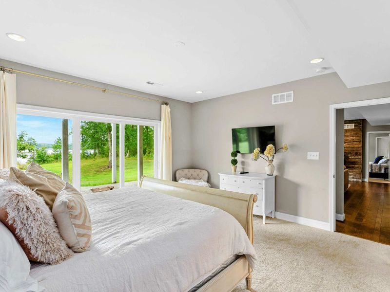 A tranquil bedroom with a king bed, cozy decor, sliding glass doors opening to a patio with lush outdoor views, and an ensuite bathroom for added convenience.