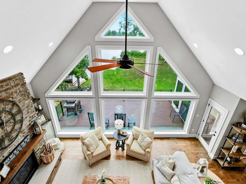 An open and airy loft space featuring a stunning view of the living room and large windows, a cozy workspace with elegant decor, and a hallway leading to private bedrooms.