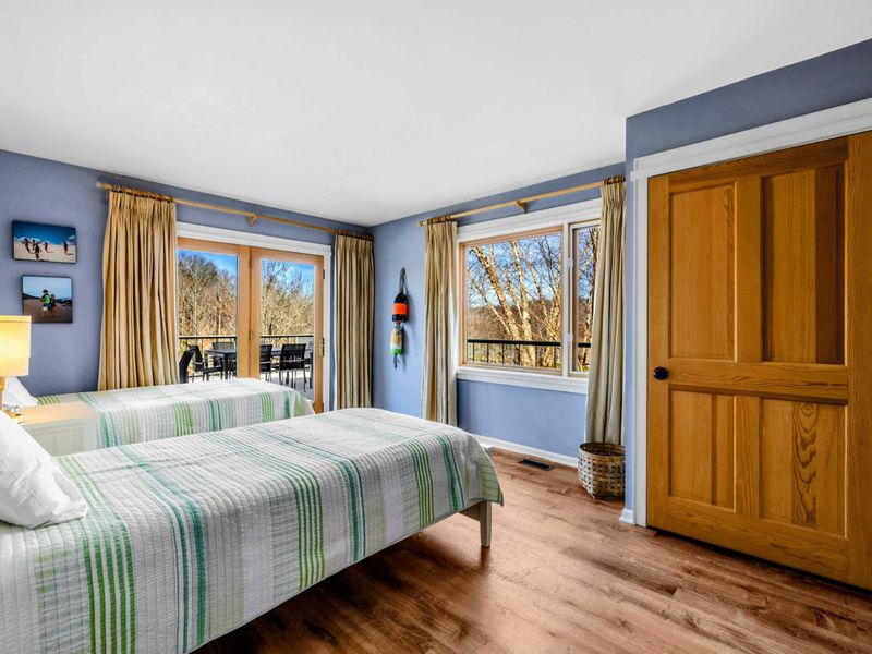 Sunny Bedroom 3 with Twin Beds & Deck Access - This bright and cozy bedroom features two twin beds, large windows with nature views, and direct access to a private deck. A peaceful retreat perfect for enjoying fresh air and the beauty of Lake Anna.