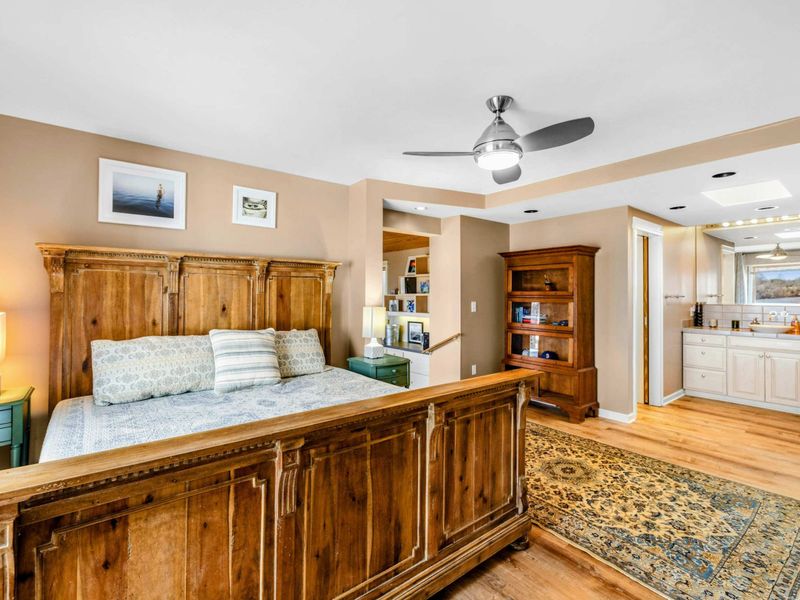 Primary Suite with Ensuite & Office Nook - This elegant Primary Suite features a luxurious king bed, a private office nook, and direct access to a spa-like ensuite with double vanities and a lake-view soaking tub for ultimate relaxation.