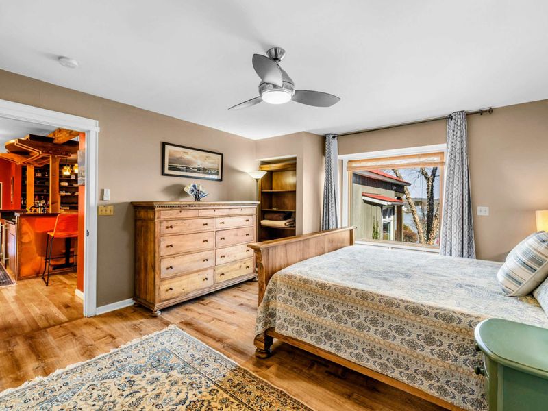 Primary Suite with Lake Views & Elegant Decor - This spacious Primary Suite features classic wood furnishings, a cozy ambiance, and large windows overlooking the lake. Enjoy easy access to the private patio and hot tub for a truly relaxing retreat.