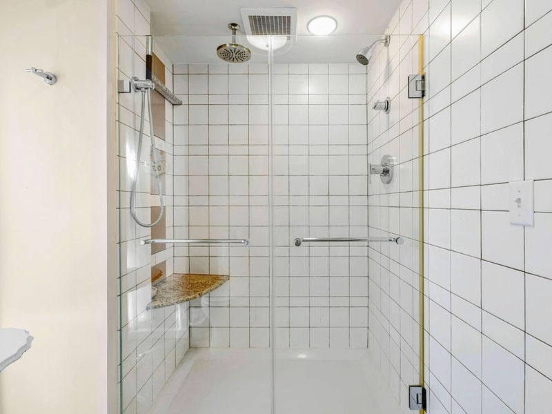 Luxury Walk-In Shower with Rainfall Head - This spacious glass-enclosed shower features sleek tilework, a rainfall showerhead, and a built-in bench for ultimate comfort. A spa-like retreat designed for relaxation and rejuvenation.