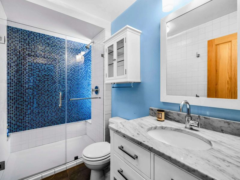 Relax in this shared upstairs bathroom between Bedrooms 3 and 4, with modern finishes and a glass-enclosed shower.
