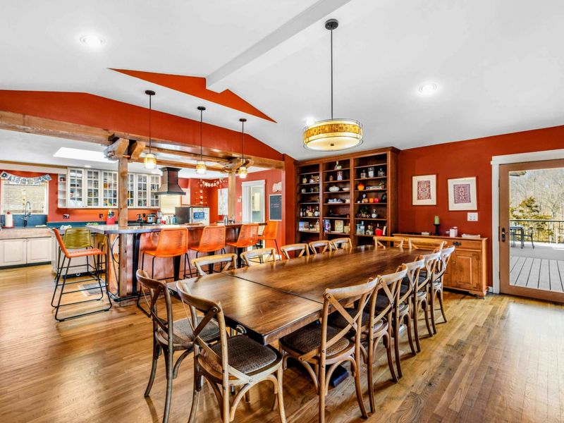 Elegant Dining Area with Deck Access - The spacious dining room features seating for 14, built-in shelving, and seamless access to the deck. The open layout connects to the kitchen and bar, making it perfect for gatherings and entertaining.