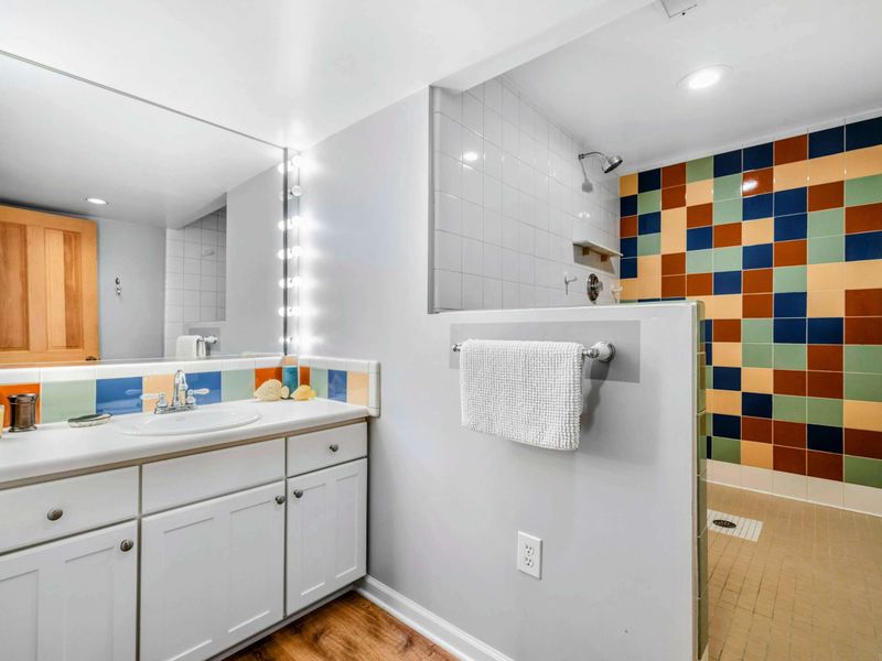 Vibrant Ensuite with Walk-In Shower - This stylish ensuite features a spacious vanity with bright lighting and a walk-in shower with colorful tile accents. A cheerful and refreshing space to start or end your day at Lake Anna.