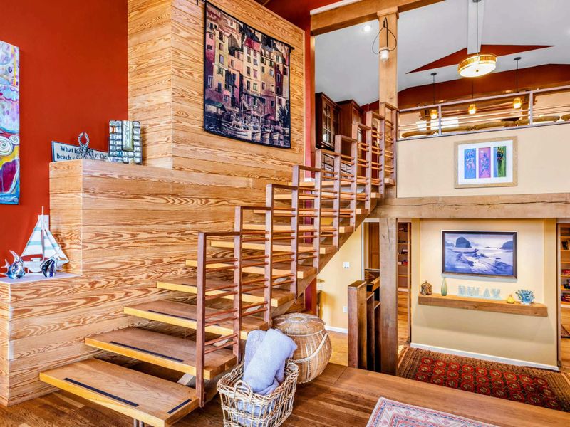This striking staircase blends modern design with rustic charm, leading to the upper level’s open loft. Warm wood tones, artistic details, and thoughtful decor create a stylish and inviting atmosphere.