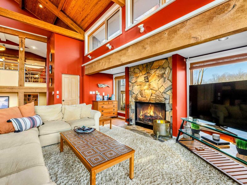 Relax in the inviting Great Room featuring a stone fireplace, plush sectional, and vaulted wood ceilings. Large windows bring in natural light, creating the perfect spot to unwind and enjoy Lake Anna.