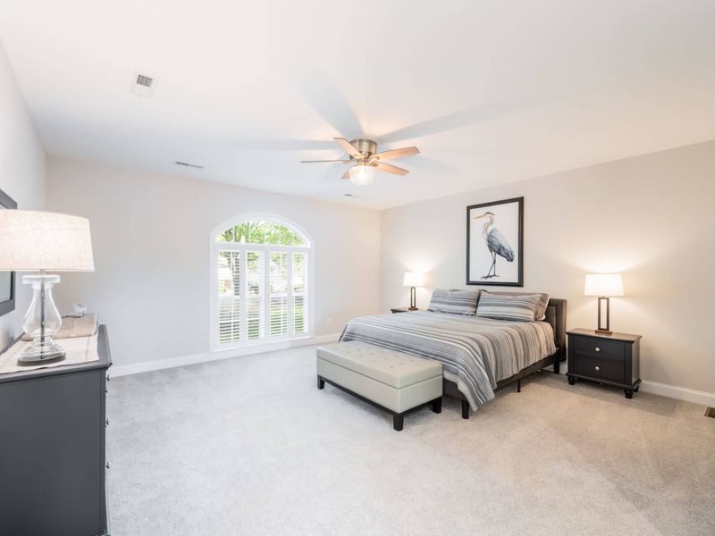 Bedroom - Two full beds with neutral striped bedding, a blue heron print, arched louvered closet, and ceiling fan.