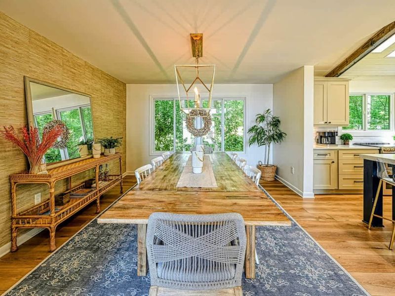 Enjoyable Dining: A spacious dining area featuring a large wooden table, natural decor accents, and abundant natural light from surrounding windows.
