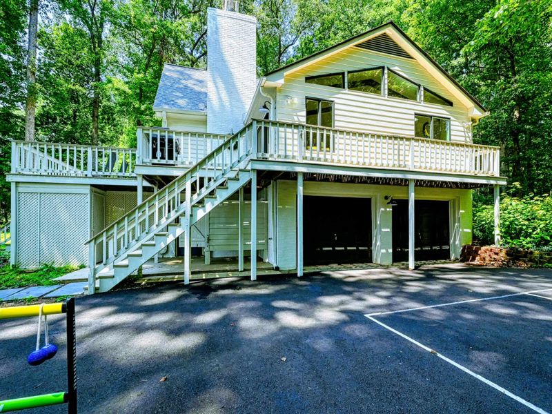 Ground Level Entry: A clean and shaded entryway into the home’s lower level, with the multi-use court nearby for pickleball fun.