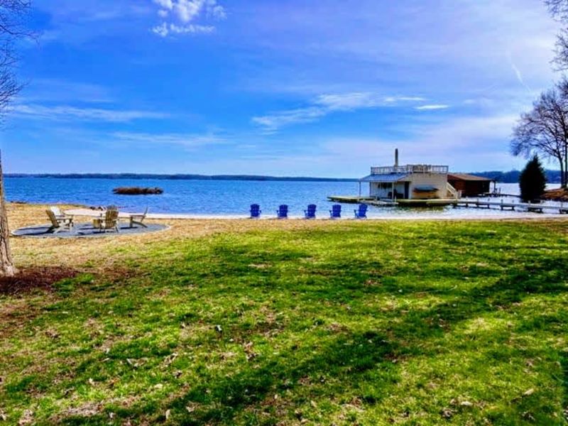 Wide-open lake views: A sprawling, flat lawn flows into a private sandy beach and dock, offering the perfect setup for games, relaxation, and soaking in the beauty of Lake Anna.
