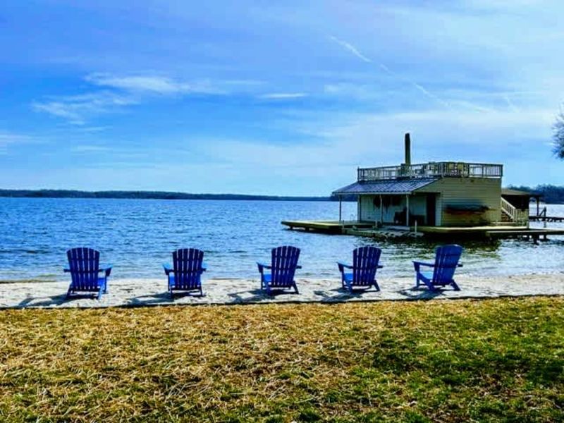 Relax and recharge: Enjoy peaceful lake views from the comfort of Adirondack chairs on your private beachfront, with the charming boathouse just steps away.