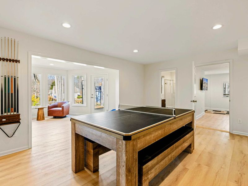 Lower Level - Pool/ping pong table with a wall-mounted cue rack, leather reading chair in a sunlit nook, and French doors to the patio.