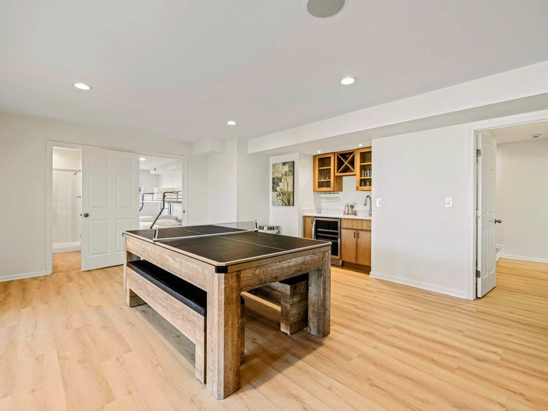 Lower Level - Convertible pool/ping pong table on a rustic wood base with a built-in wet bar and wine rack beyond.