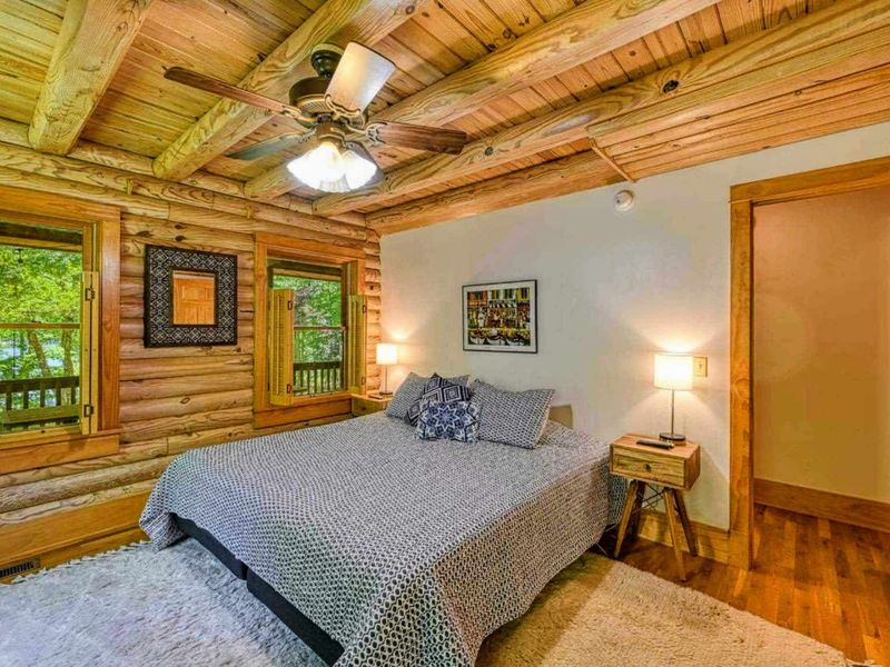 Relax in this cozy log cabin-style bedroom with beautiful natural views and comfortable furnishings for a peaceful night's sleep.