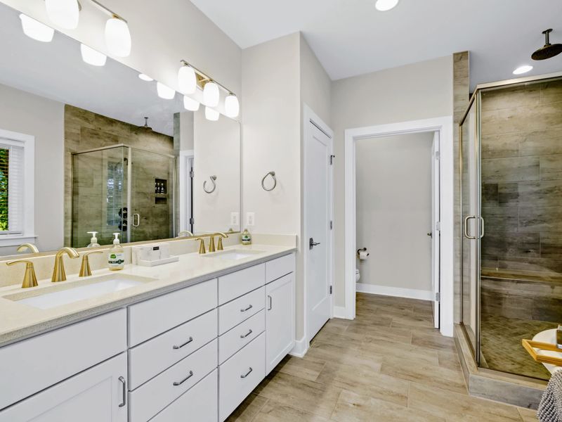 Primary Bath - Double vanity with brushed gold fixtures and a walk-in tile shower with rainfall head, more spa than functional.