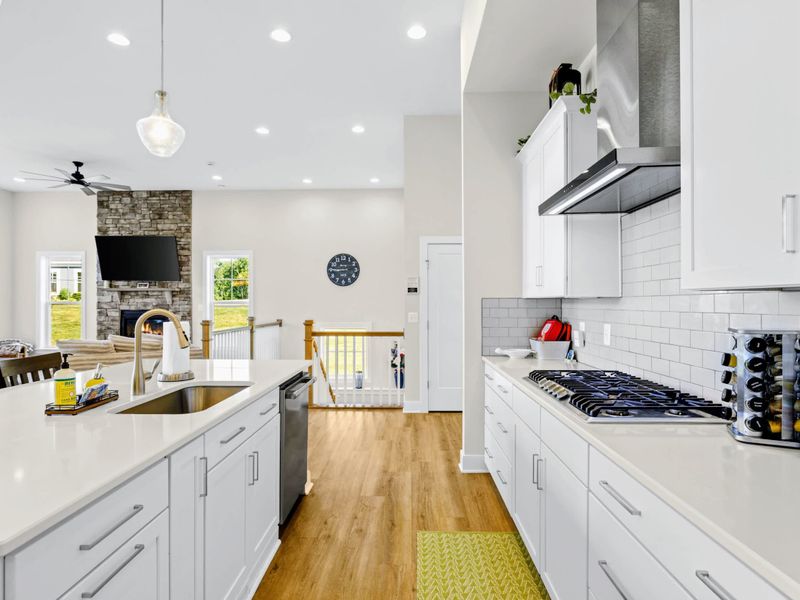 Kitchen - Long galley run with cooktop, double ovens, and a clear sightline to the fireplace and the rest of the gathering.