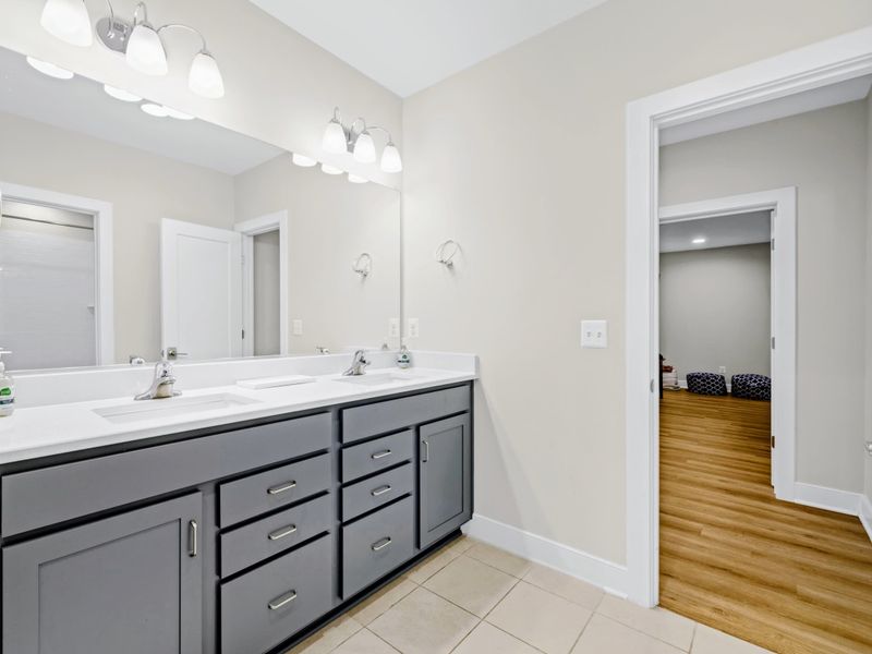 Suite 4 Bath - Double vanity with a bright mirror, side-by-side sinks, and tub-shower combo behind the door.