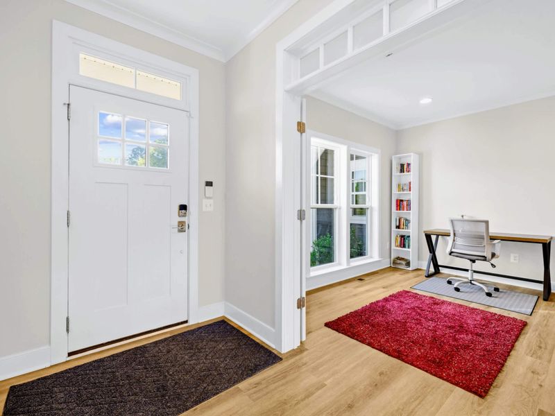 Office - Bright work nook off the front entry with a writing desk, ergonomic chair, and a small bookcase by the window.