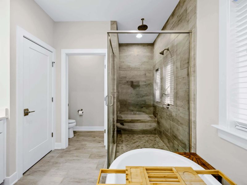Primary Bath - Walk-in tile shower with rainfall head and the freestanding soaking tub beside the private water closet.