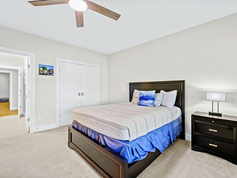 Suite 4 - Queen bed with a dark wood frame, double closets, and hallway access leading toward the lake-level rec room.
