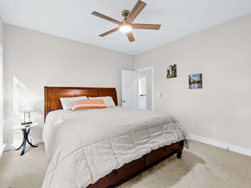 Suite 3 - Queen bed with a rich wood sleigh headboard, side table, and the doorway to a shared bath.