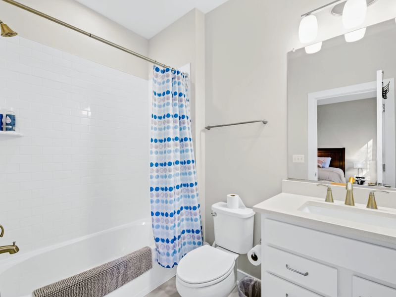 Suite 3 Bath - White subway tile tub-shower combo with brushed gold fixtures and a bright single vanity.