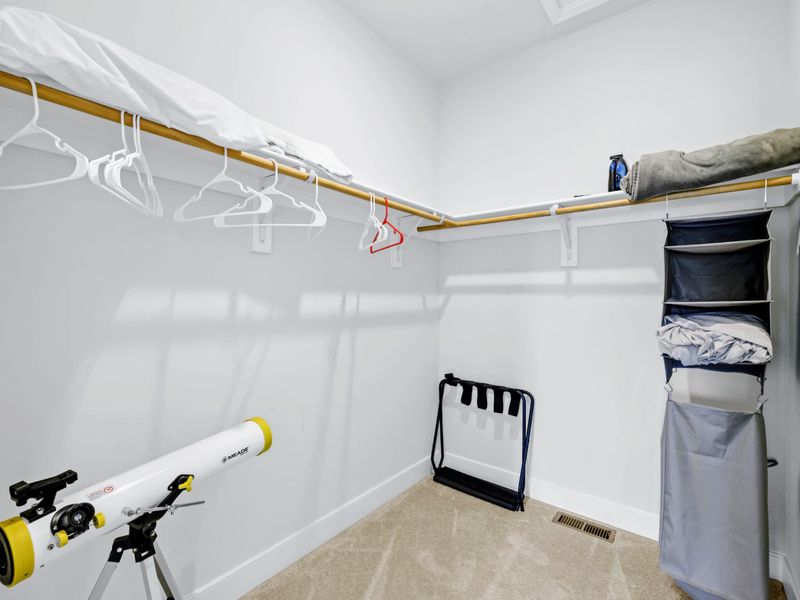 Primary Suite - Walk-in closet with hanging rods, luggage rack, and shelf storage, set up so a long stay still feels easy.