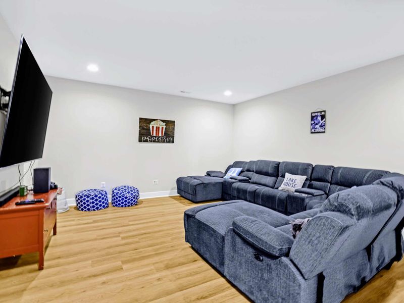 Theater - Big screen, deep blue sectional with cup-holder recliners, and popcorn art on the wall, ready for movie night.
