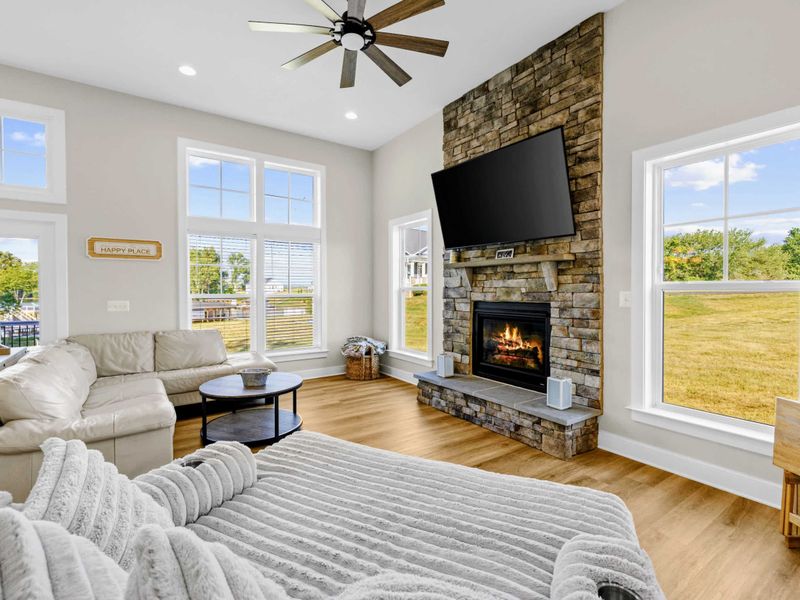 Great Room - Leather sofa, plush lounger, and the stone fireplace in the back, all bathed in natural light from the yard.