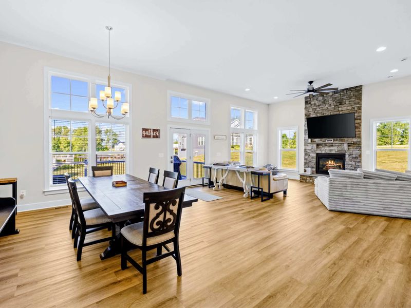 Dining Area - Six-seat farmhouse table beside the stone fireplace, with deck and yard views through the wall of windows.