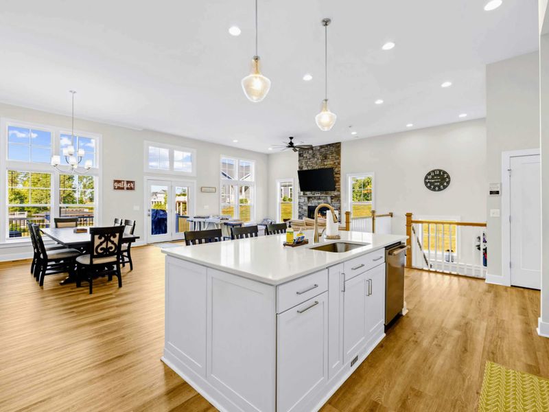 Kitchen - Wide bar-top island with prep sink and dishwasher faces the dining table and the wall of windows past it.